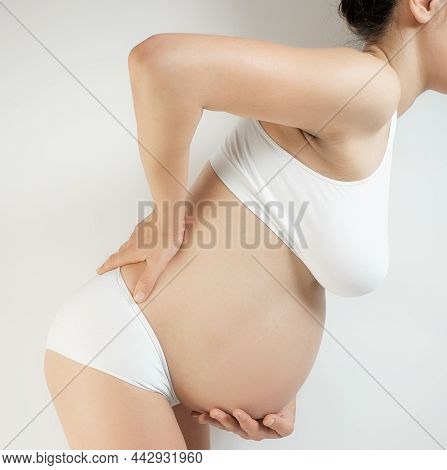 Lady In The Third Trimester Of Pregnancy. A Pregnant Woman In White Underwear Grabbed Her Belly And 