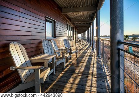 Sunrise shadows on long porch with Adirondack chairs overlooking beautiful view.