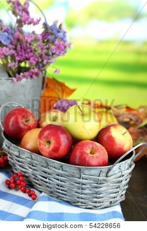 Juicy apples in basket on table on natural background