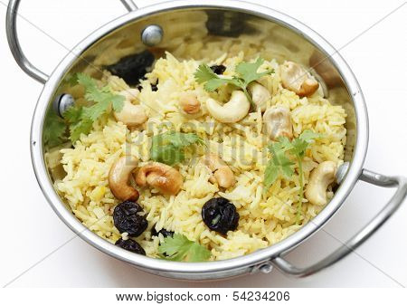 Raisin and cashew pilaf, made with basmati rice and garnished with coriander leaves, served in a traditional indian kadai dish