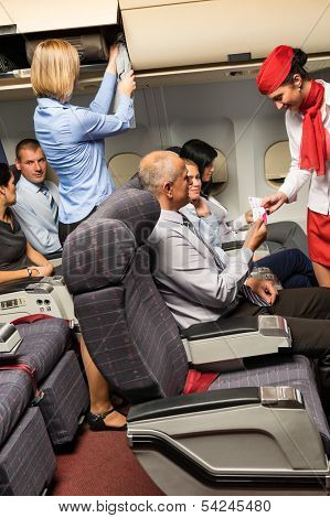 Flight attendant check passenger tickets in plane cabin