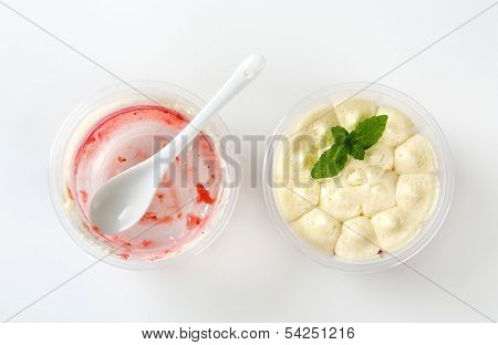 two plastic cups - one filled with yogurt, one empty