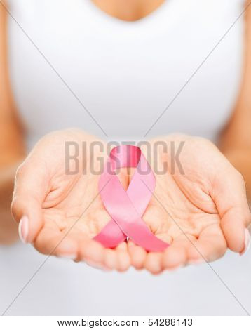 healthcare and medicine concept - womans hands holding pink breast cancer awareness ribbon