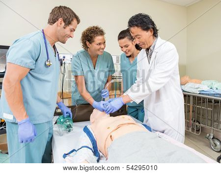 Smiling medical team adjusting endotracheal tube in dummy patient's mouth at hospital room