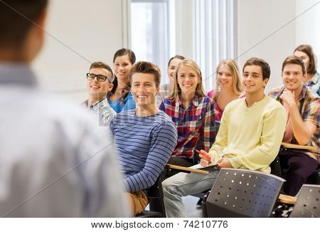 education, high school, teamwork and people concept - group of smiling students with notebooks and teacher in classroom