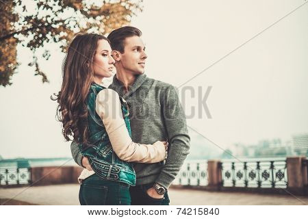 Beautiful young couple near river on autumn fogy day 