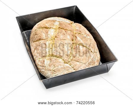 Loaf of home baked bread in baking tin over white background