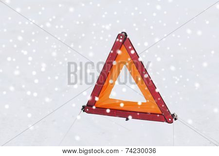 transportation and winter concept - closeup of warning triangle on snow