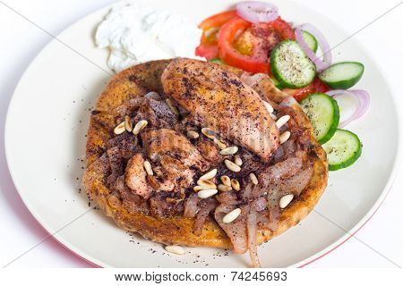 Musakhan, traditional Palestinian sumac chicken, on a plate with a salad and yoghurt,