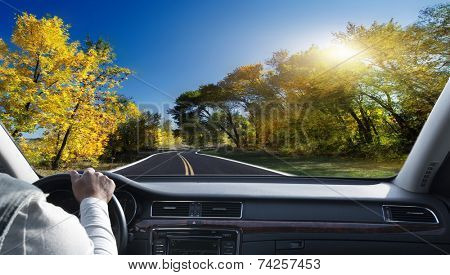 Hands on steering wheel of a car driving on an asphalt road 