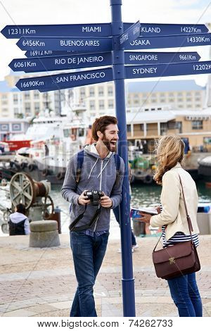 couple on travel holiday at sign with guide book