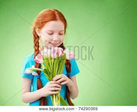 Adorable girl looking at bunch of tulips in her hands