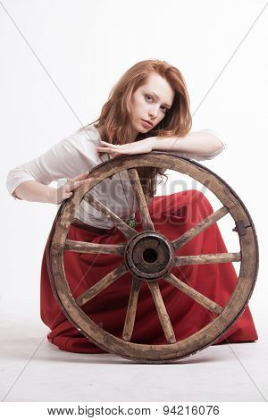young woman with an old wagon wheel on white background