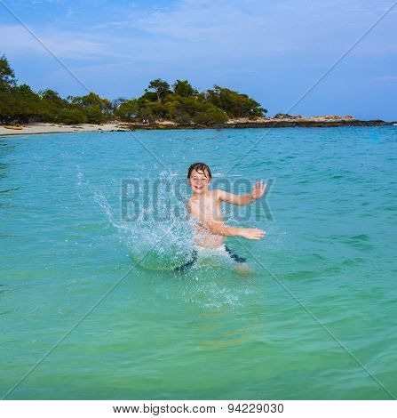Handsome Boy Enjoys Sputtering With His Hand In The Tropical Ocean