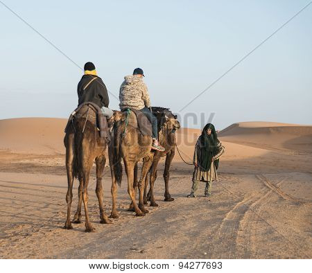 The Arabian Guide With Couple Of Tourist In Sahara Desert
