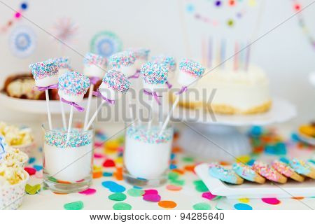 Cake, candies, marshmallows, cakepops, fruits and other sweets on dessert table at kids birthday party