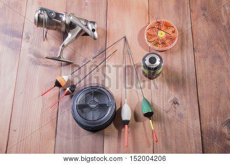 Fishing accessories reel spools of fishing line floats and a box of hooks on wooden background
