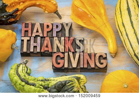 Happy Thanksgiving - a greeting card or banner in vintage letterpress wood type blocks against wood with gourd and winter squash
