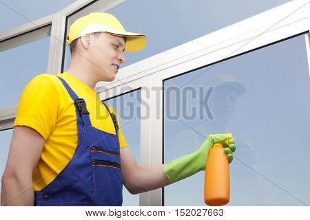 Professional cleaning. Young man washes window