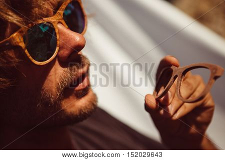Portrait of handsome beraded man in sunglasses looking on wooden rim glasses