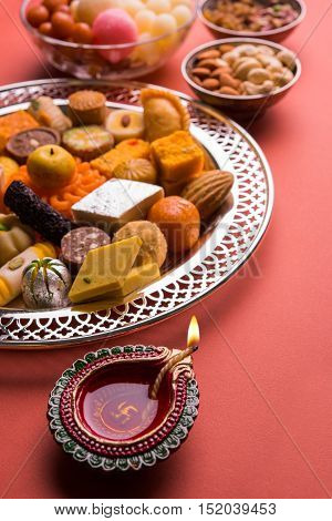 Mix Mithai and diya on diwali over colourful background