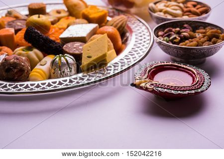 Mix Mithai and diya on diwali over colourful background