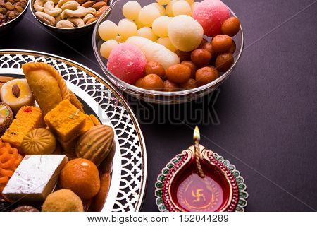 Mix Mithai and diya on diwali over colourful background