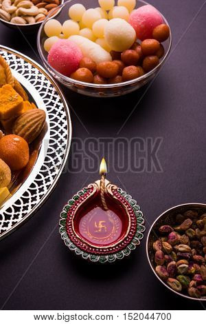 Mix Mithai and diya on diwali over colourful background