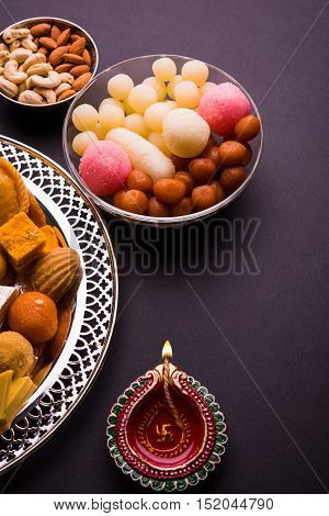 Mix Mithai and diya on diwali over colourful background