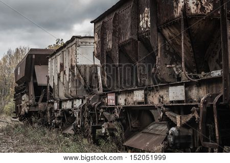 Abandoned train set still standing on the old track trees and bushes begin to grow through.