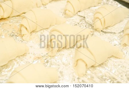 Several homemade raw croissants on the foil