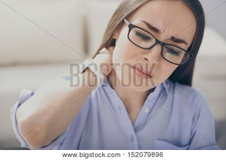 Need some sleep.Brunette bespectacled woman closing eyes and touching neck while feeling tired.