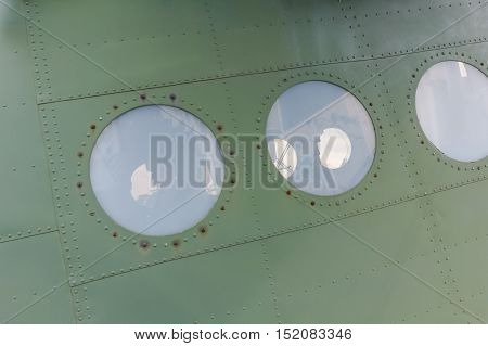Window in old airplane aluminum background detail of a military porthole aircraft