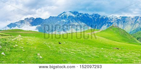 The expanses of Kazbegi National Park with the Gergeti Trinity Church and the snowbound peaks of Greater Caucasus Range on the background Georgia.