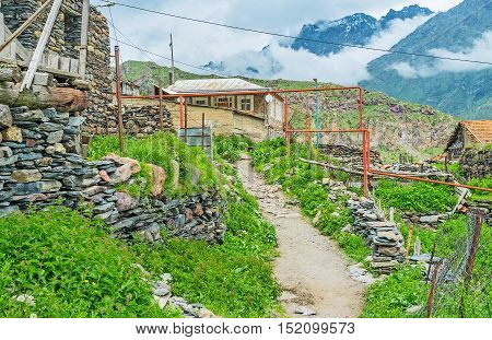 The old village footpath leads to the Kazbegi National Park along the old stone houses and kitchen-gardens Stepantsminda Georgia.