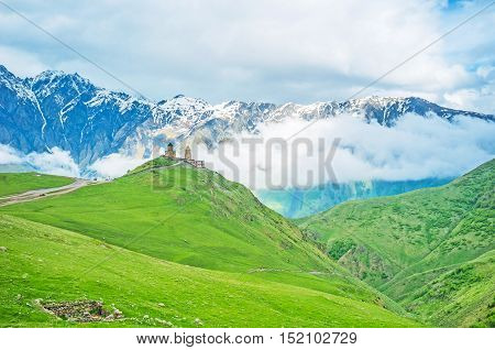 The weather in Kazbegi National Park changes very fast the clouds descend into the valley creating unique background for the Gergeti Trinity Church Georgia.