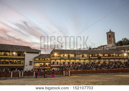 Chinchon Spain - October 15 2016: Plaza square Mayor of Chinchon adapted as a bullring Detail of balconies illuminated dressed with the Spanish flag beautiful sunset at Chinchon Spain