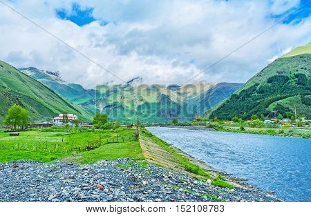 The walk along the bank of the Snostskali river in Sno gorge with the view on the medieval castle on the background Georgia.