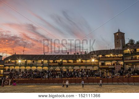 Chinchon Spain - October 15 2016: Plaza square Mayor of Chinchon adapted as a bullring Detail of balconies illuminated dressed with the Spanish flag beautiful sunset at Chinchon Spain