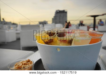 rainbow cocktail shotes serve in ice bucket in evening twilight nature light with background as business men hangout with friends - backlight pic with soft and select focus