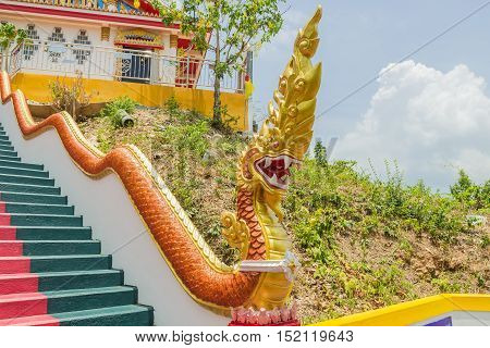 Phuket Thailand - April 25 2016 : Yellow Naka (giant snake) statue on top of main stair leading to the replica of Phra That In-Kwaen (Hanging Golden Rock) at Sirey temple Phuket Thailand.