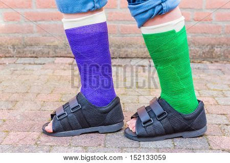 Standing teenage boy with two colored gypsum legs outside