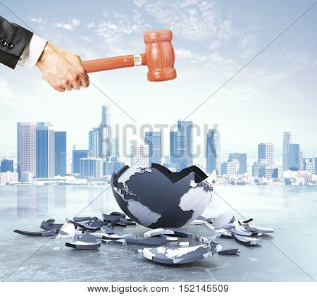 Businessman hand cracking terrestrial globe with wooden hammer on city background. World destruction concept. 3D Rendering