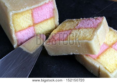 Freshly Cut Battenberg Cake On Dark Slate Background With Cake Slice. Pink And Yellow Sponge Covered