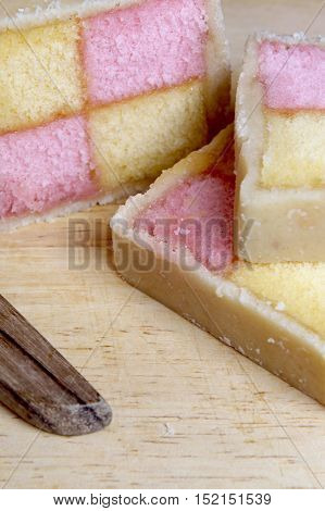 Freshly Cut Battenberg Cake With Knife. Pink And Yellow Sponge Covered In Marzipan