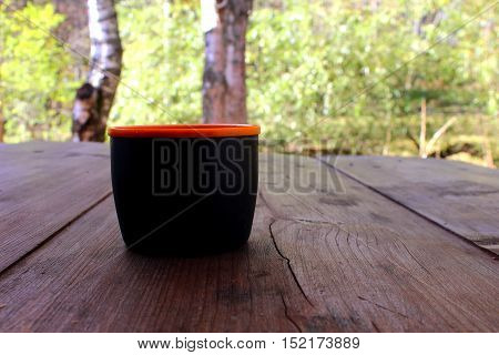 A cup with a hot drink on a wooden table outdoors