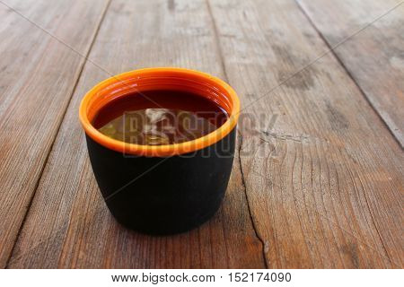 A cup with a hot drink on a wooden table outdoors