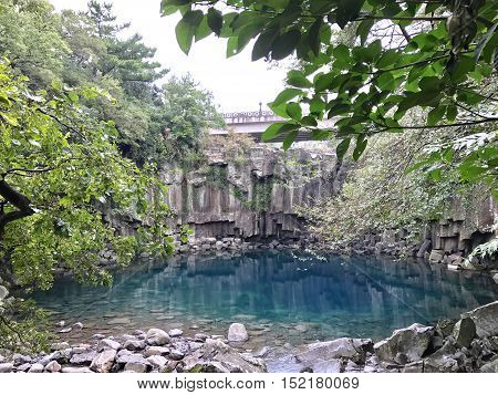 An all natural serenity pool with aqua clear blue water. Photo taken at Cheonjiyeon Falls in Jeju Island, Korea on October, 2016.
