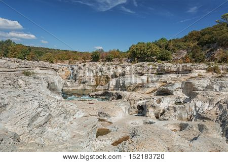 At the foot of the hill on which La Roque sur Cèze in France lies swirl spectacular waterfalls and rapids of the Cascades du Sautadet.