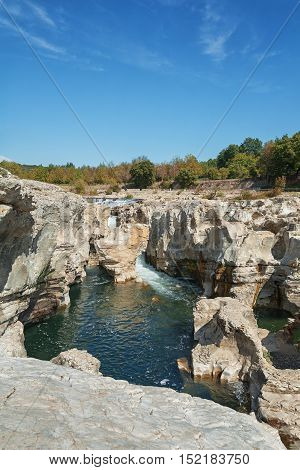 At the foot of the hill on which La Roque sur Cèze in France lies swirl spectacular waterfalls and rapids of the Cascades du Sautadet.